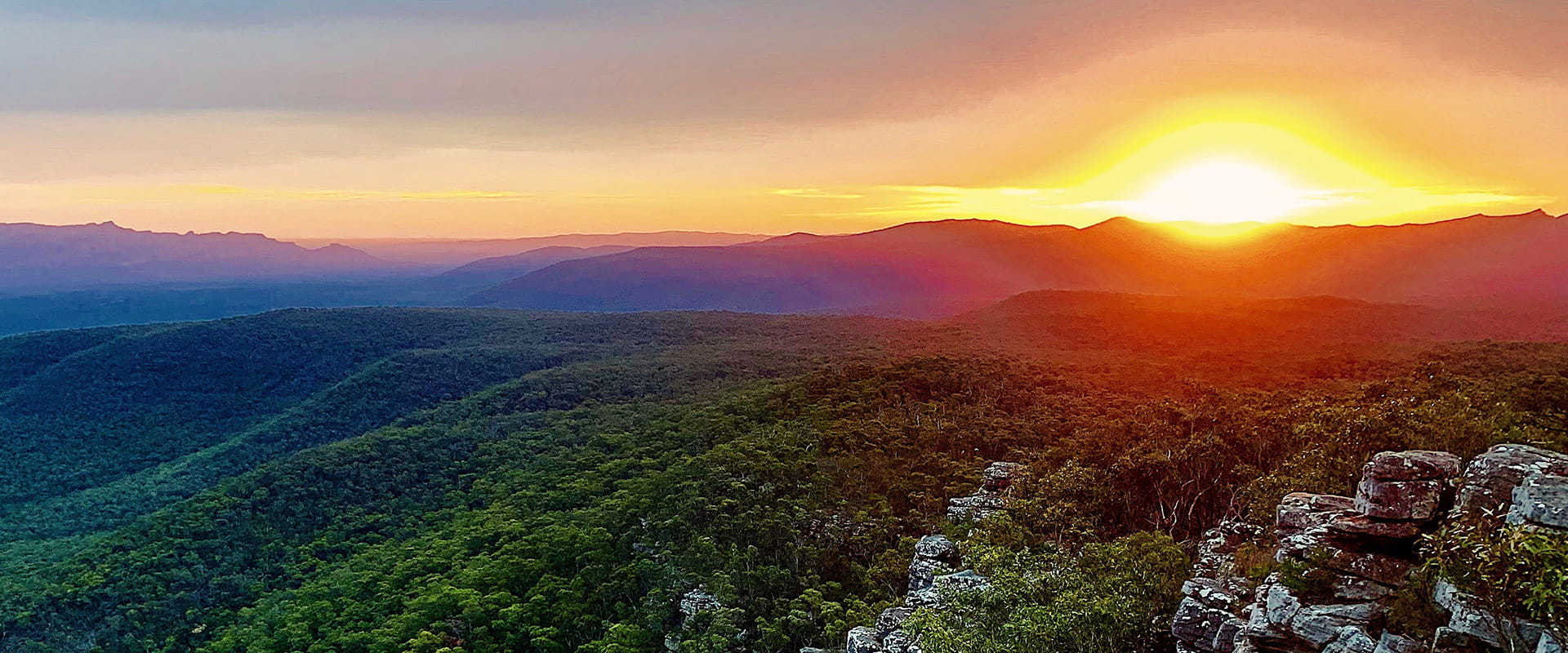 Sunset over foliage-covered mountain range.