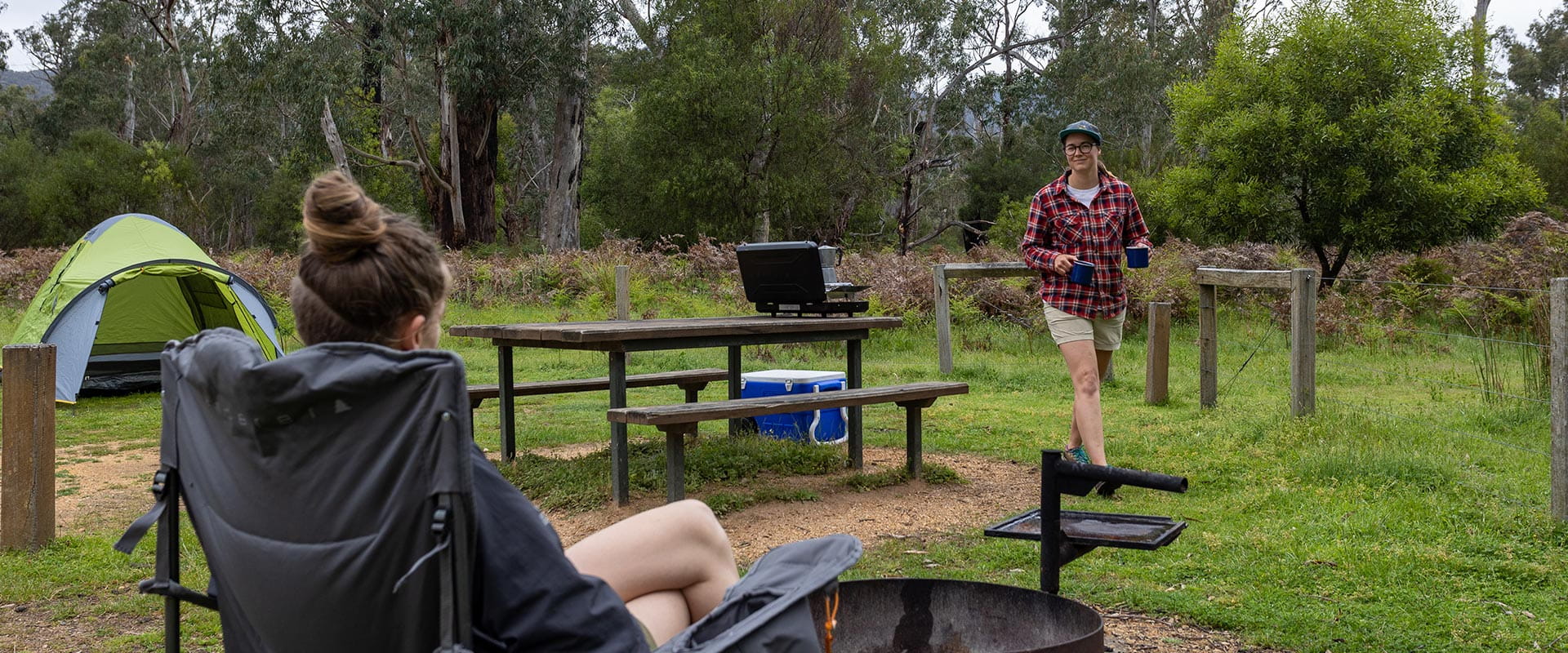 Two hikers relax in a grassy campground