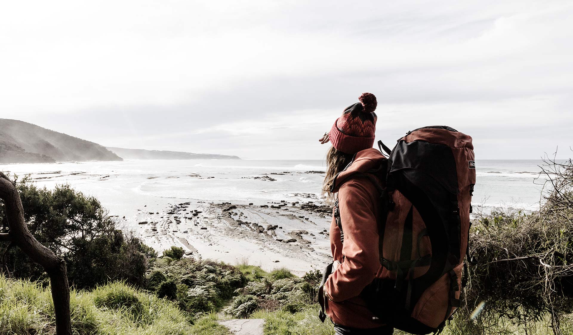 A woman with a large hiking pack takes in the view from Blanket Bay Campground.