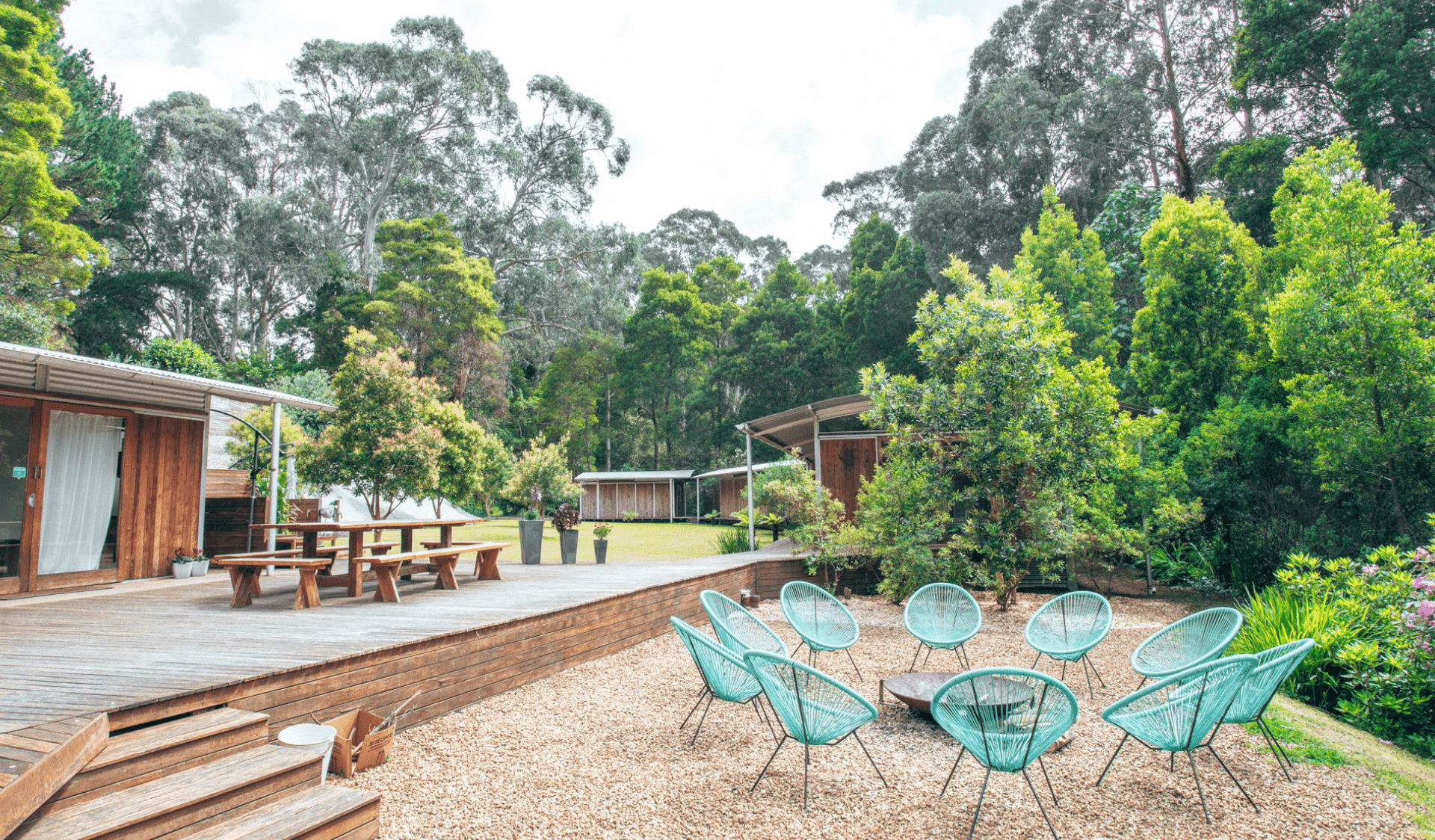 Chairs surround a firepit with cabins surrounded by trees in the background