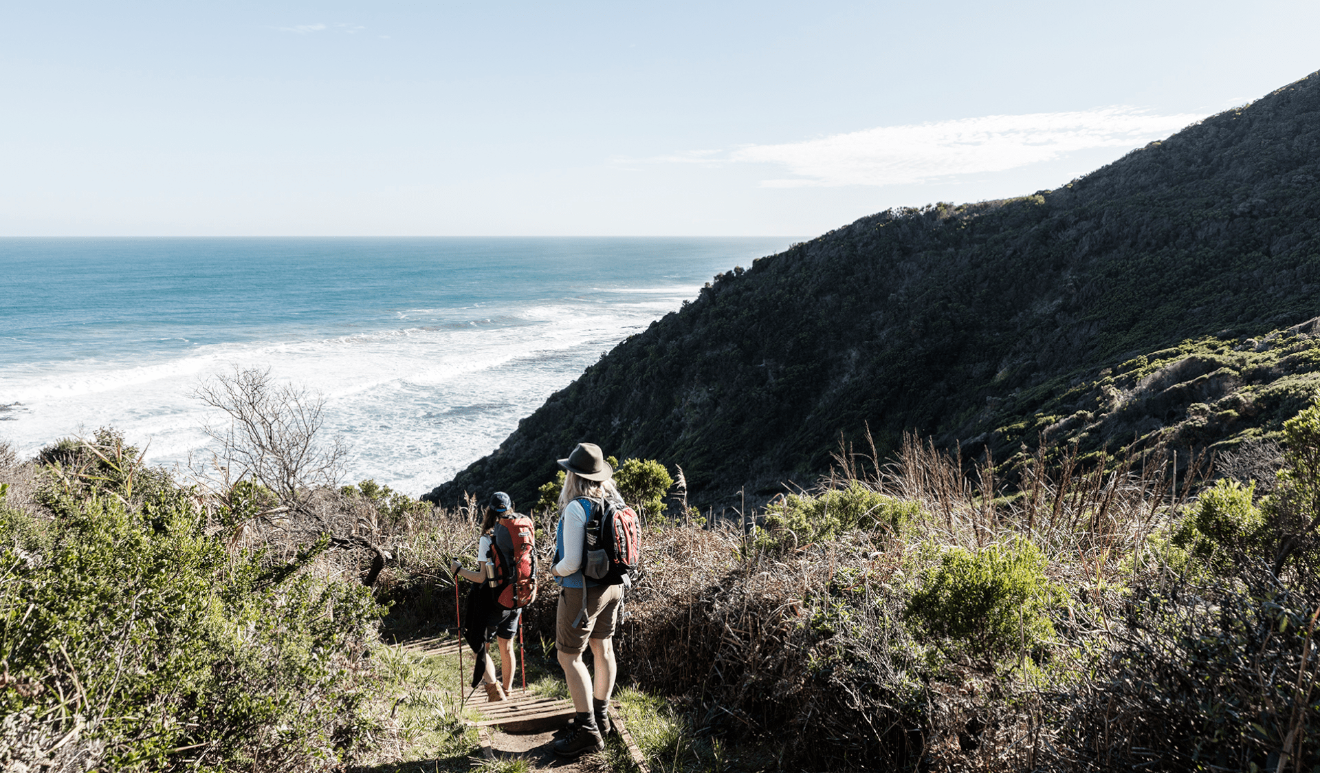 Two female hikers follow the Great Ocean Walk trail down to Wreck Beach