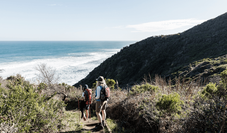 Two female hikers follow the Great Ocean Walk trail down to Wreck Beach