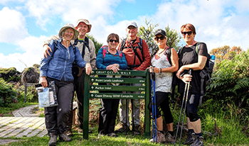 A group of hikers gathers around a Great Ocean Walk sign