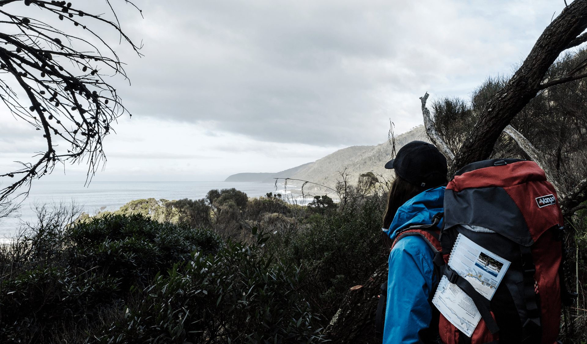 A female hiker with a large backpack looks out from the Great Ocean Walk walking track