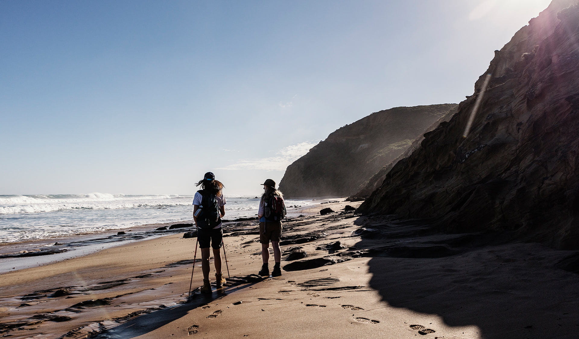 Two women walk along the sand during a section of the Great Ocean Walk.