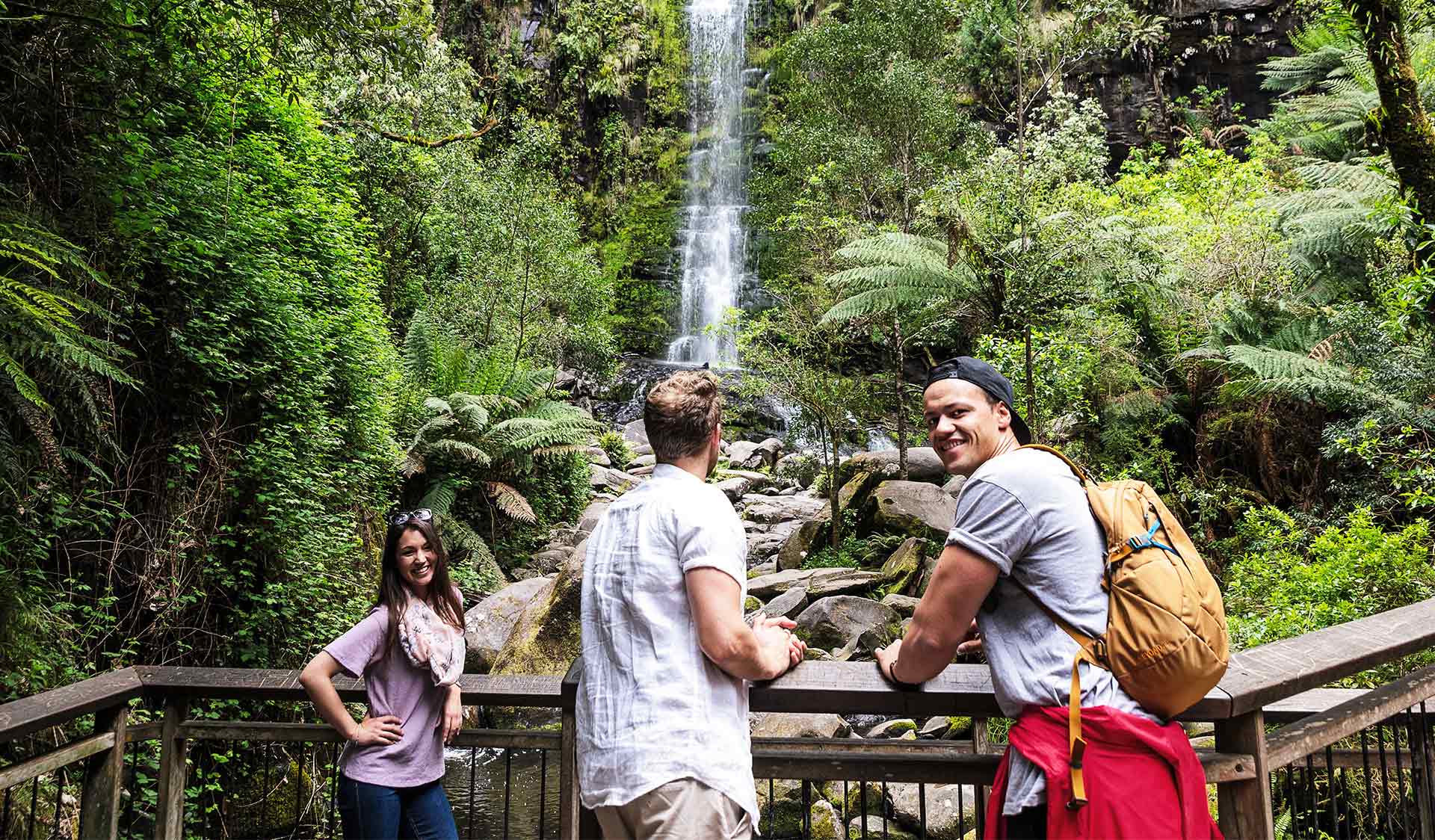 Three friends standing at the Erskine Falls lookout admiring the waterfall.