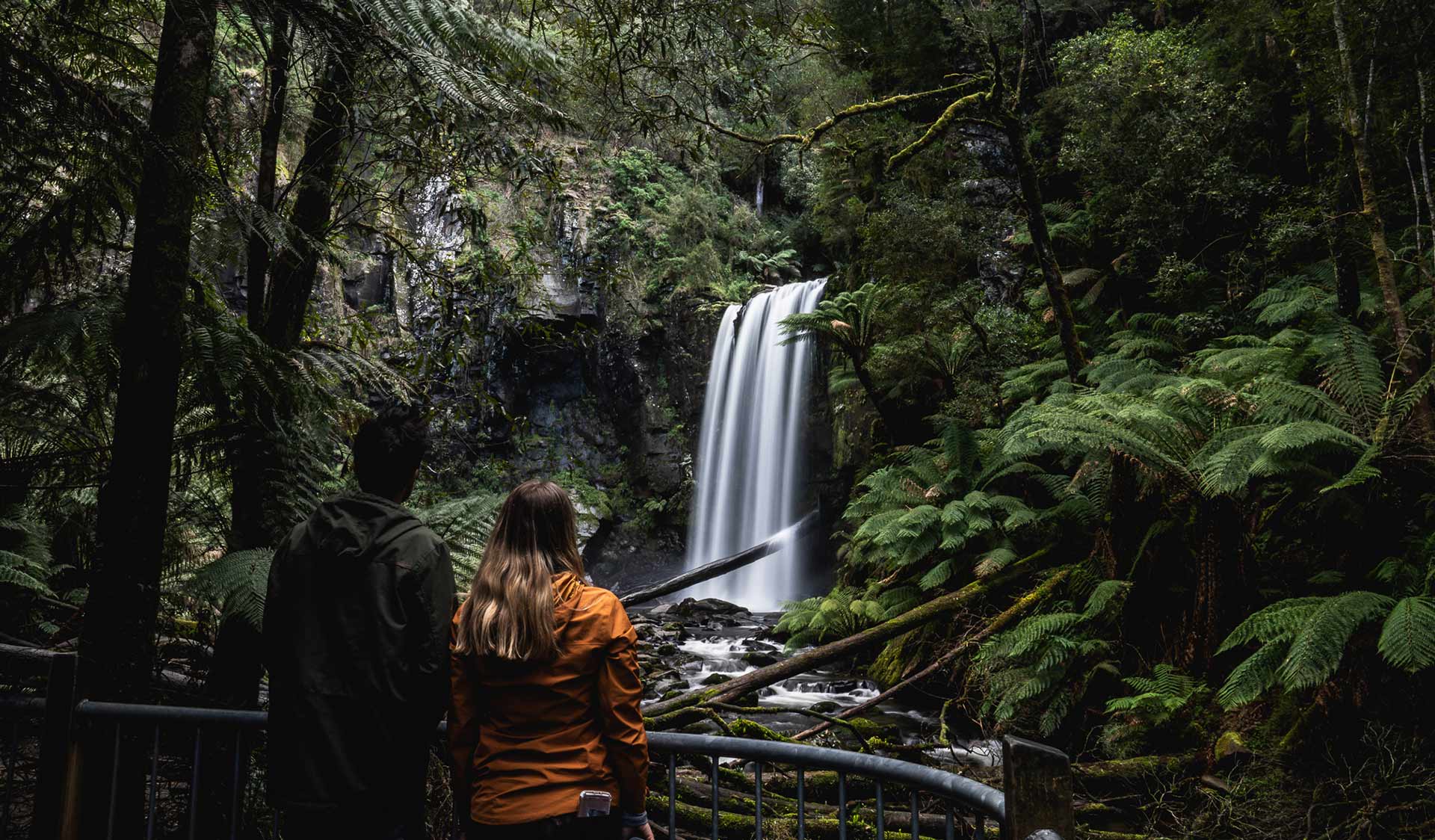 A couple look on at a Waterfall in the Great Otway National Park. 