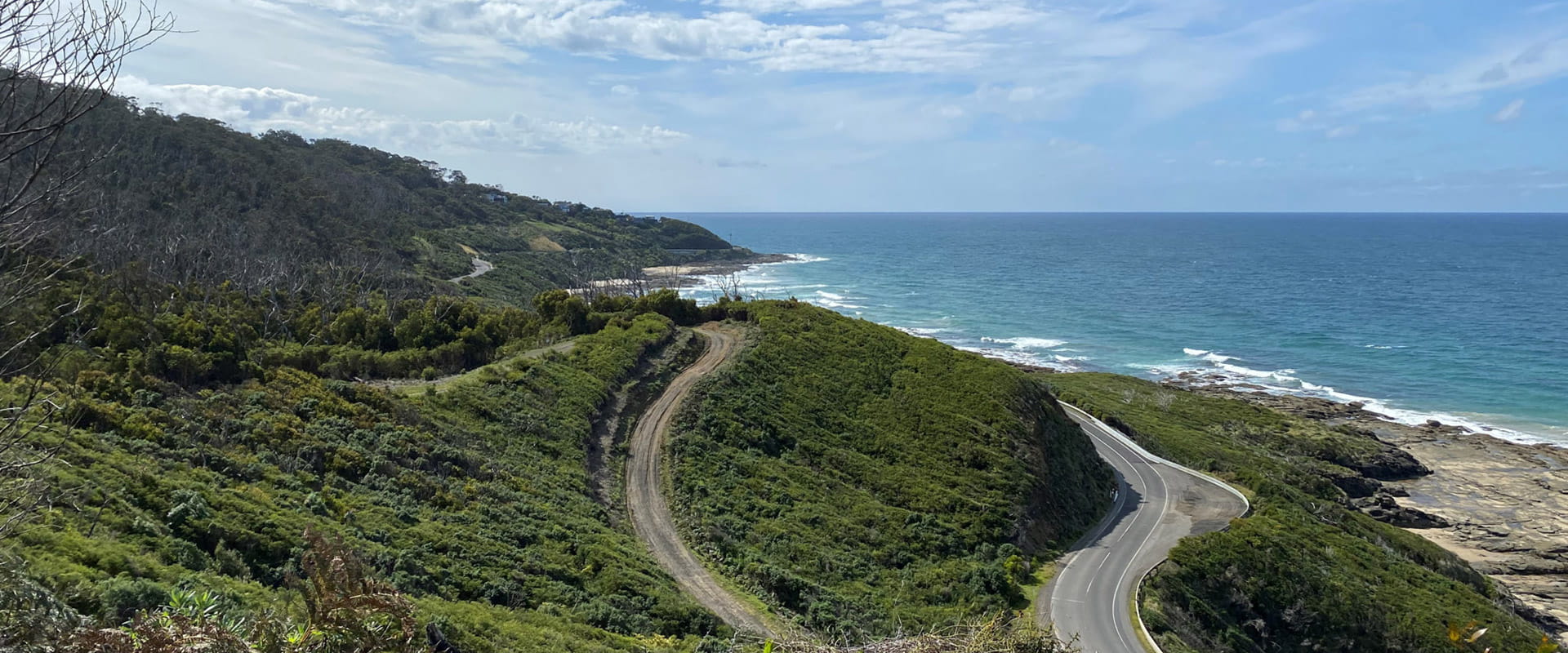 A dirt path winds down out of the Otways towards a large ocean view
