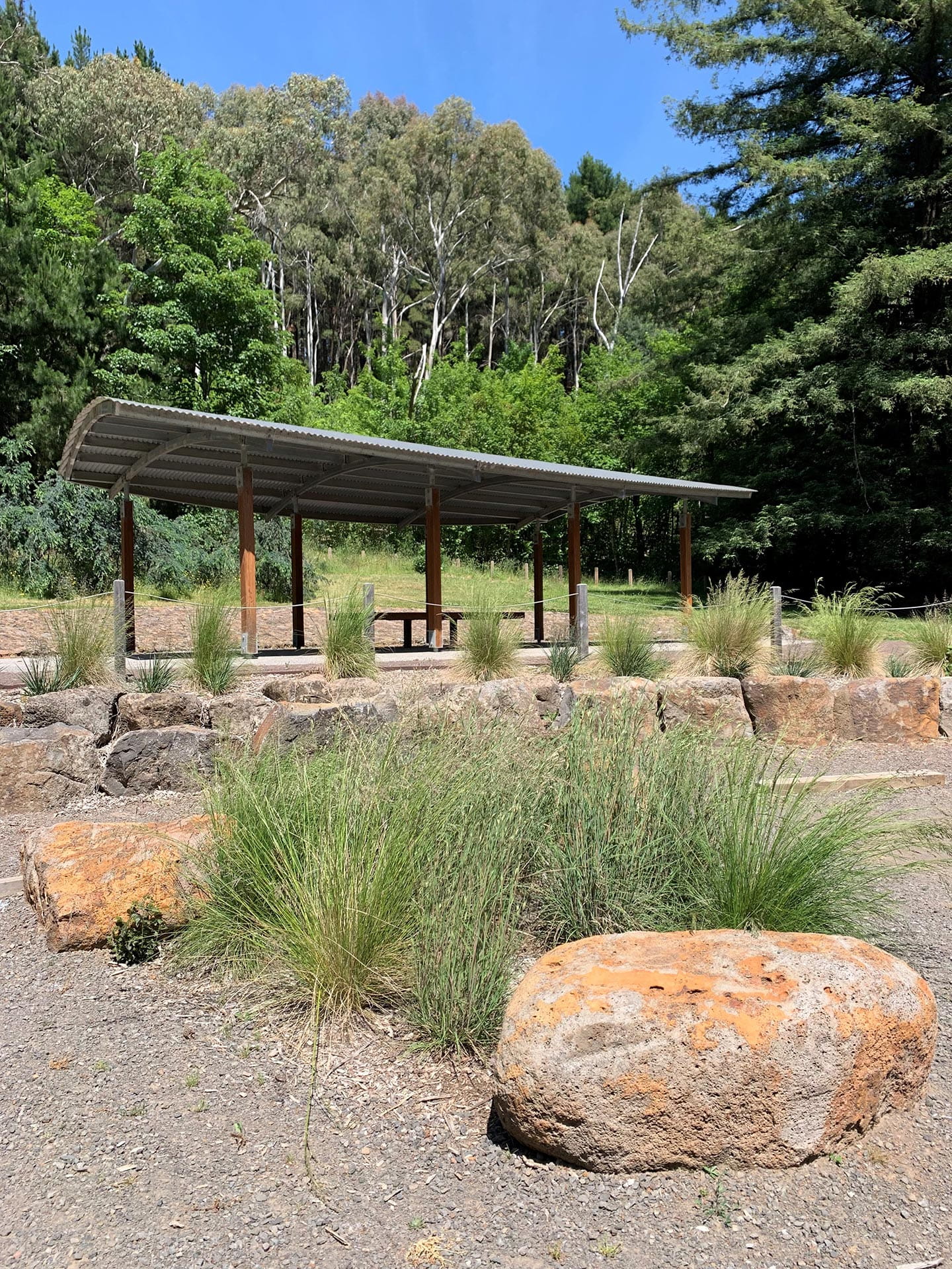 A shelter in a landscaped area with trees in the background.