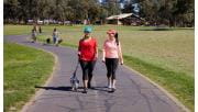 A woman and friend in activewear walking a small dog at Jells Park