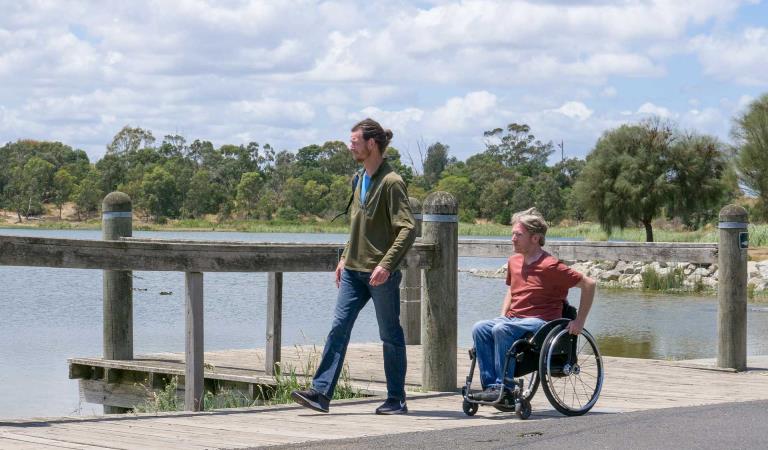 Two men walk along the edge of a fishing jetty at Karkarook Park