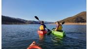 A young couple paddle kayaks on a sunny afternoon across Lake Eildon.