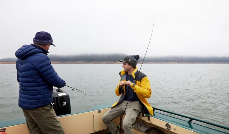 Two friends fish off the back a boat on a misty morning on Lake Eildon.