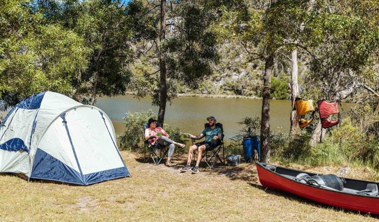 Two campers relax at their campsite after a long paddle.