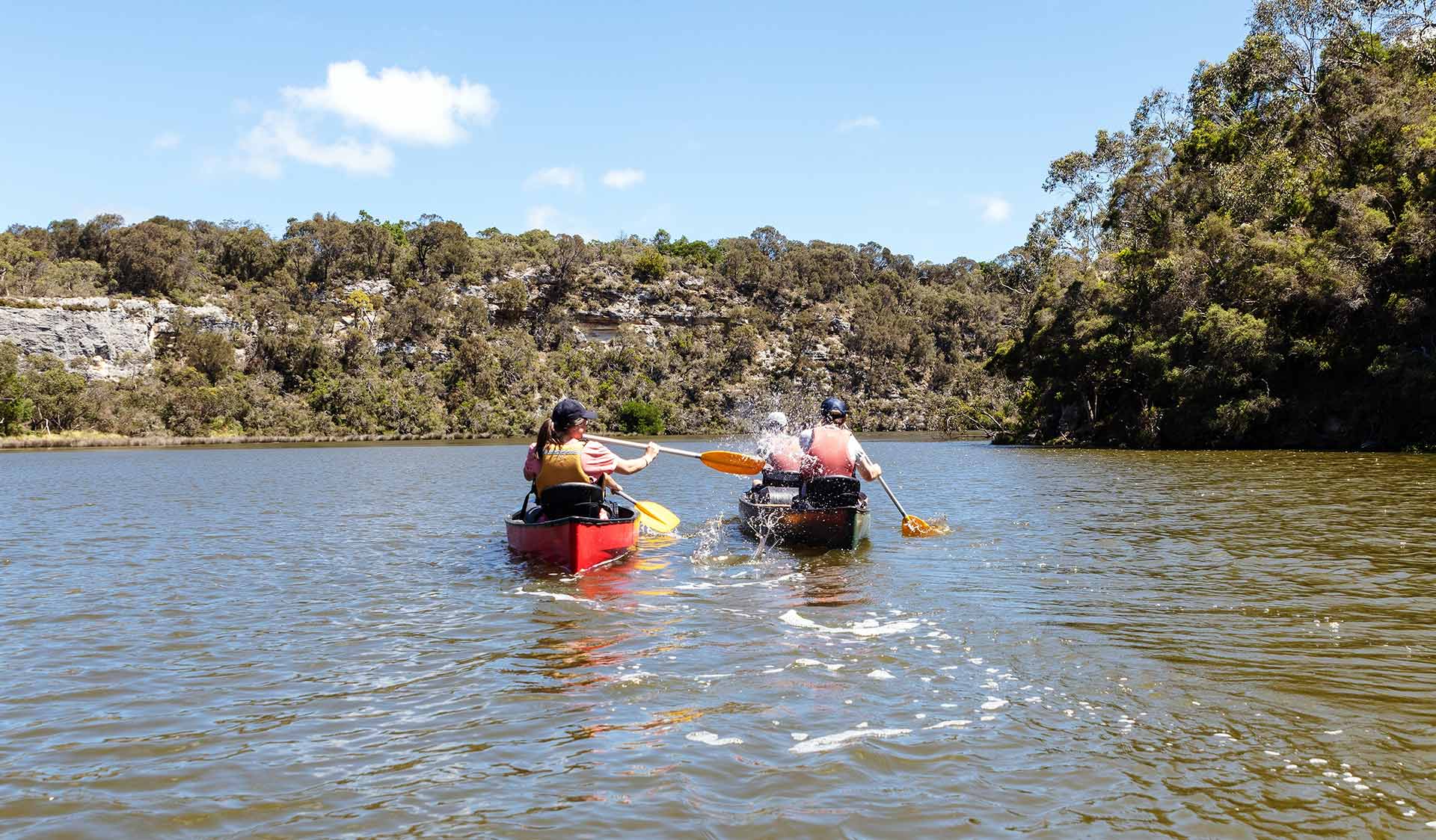 A woman playfully splashing a friend in another canoe with her paddle on the Glenelg River