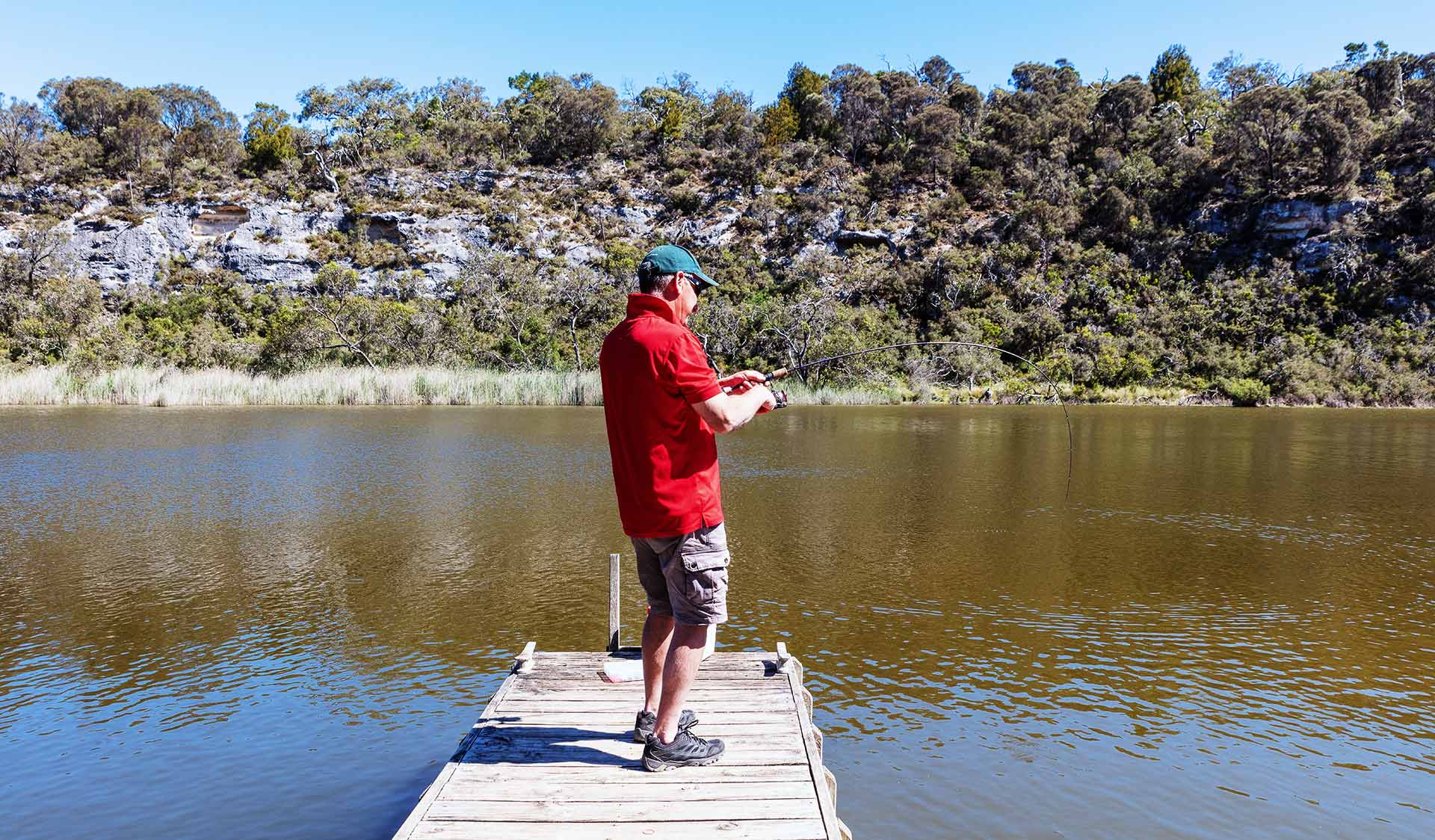 A man fishes from a jetty in the Glenelg River.