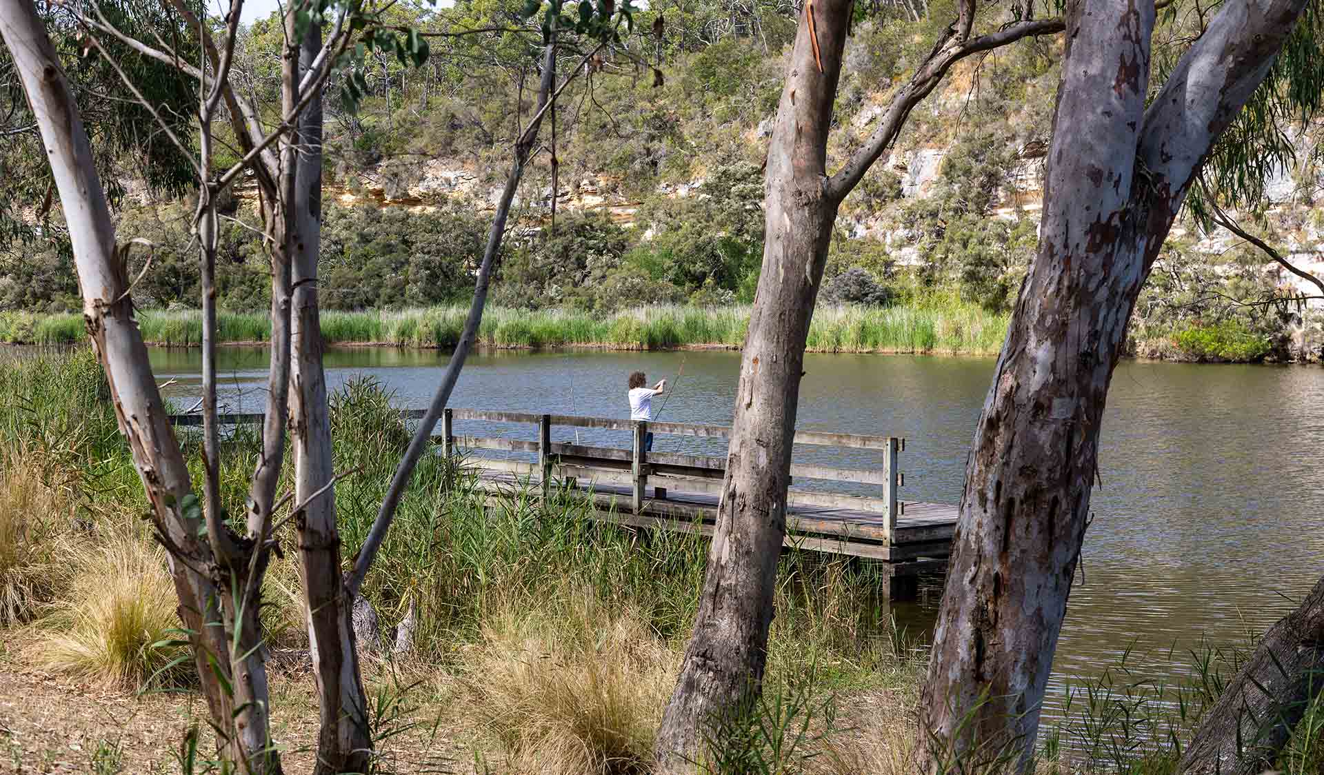 A man fishes of the jetty at Mclennans Punt Campground at Lower Glenelg National Park