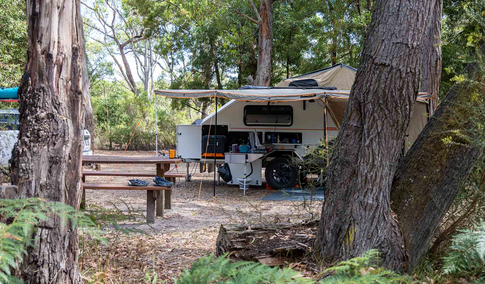 A camper trailer pictured between two trees at Wilson Hall Campground at Lower Glenelg National Park