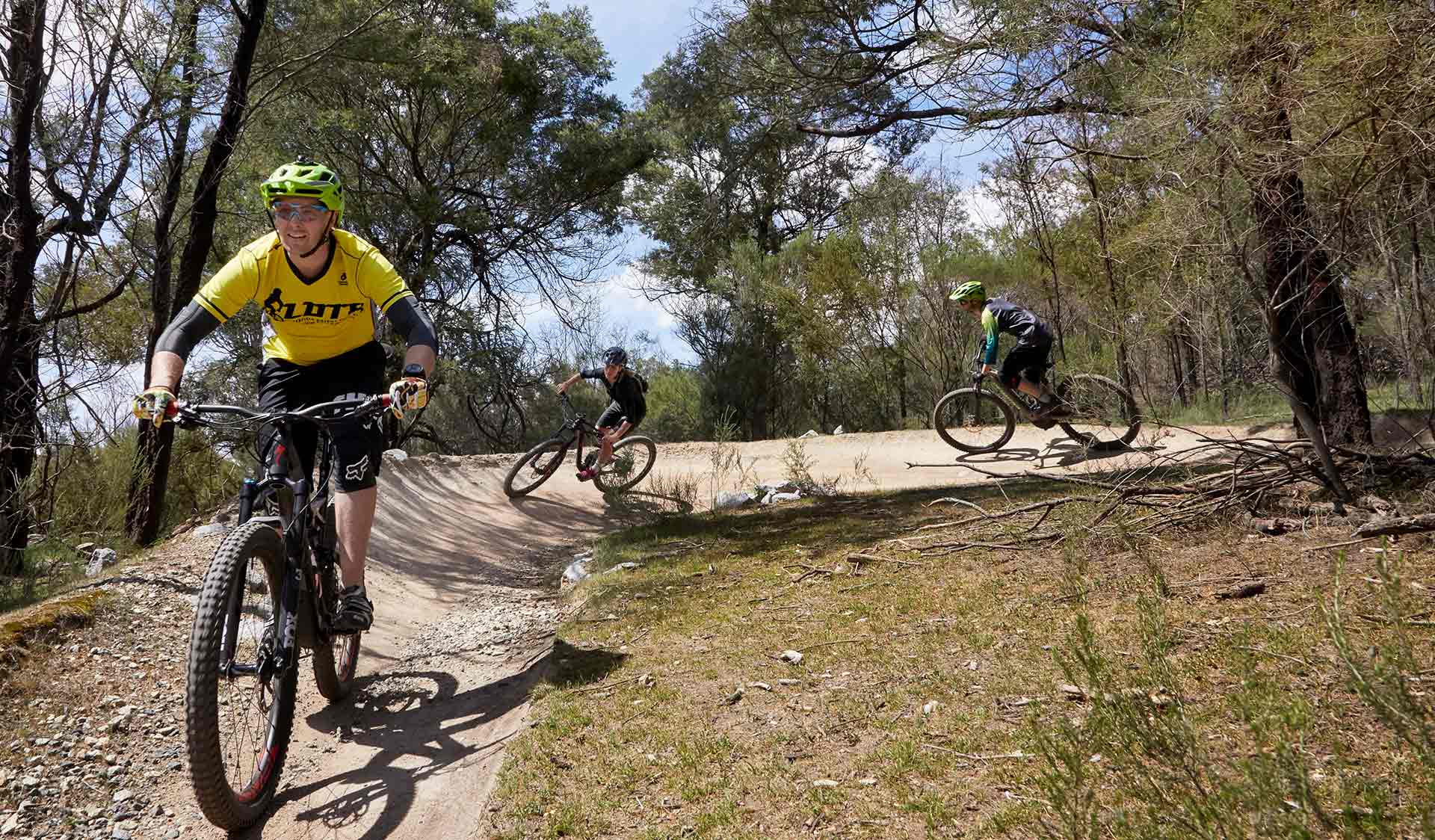 Three mountain bikers turn left through a berm.