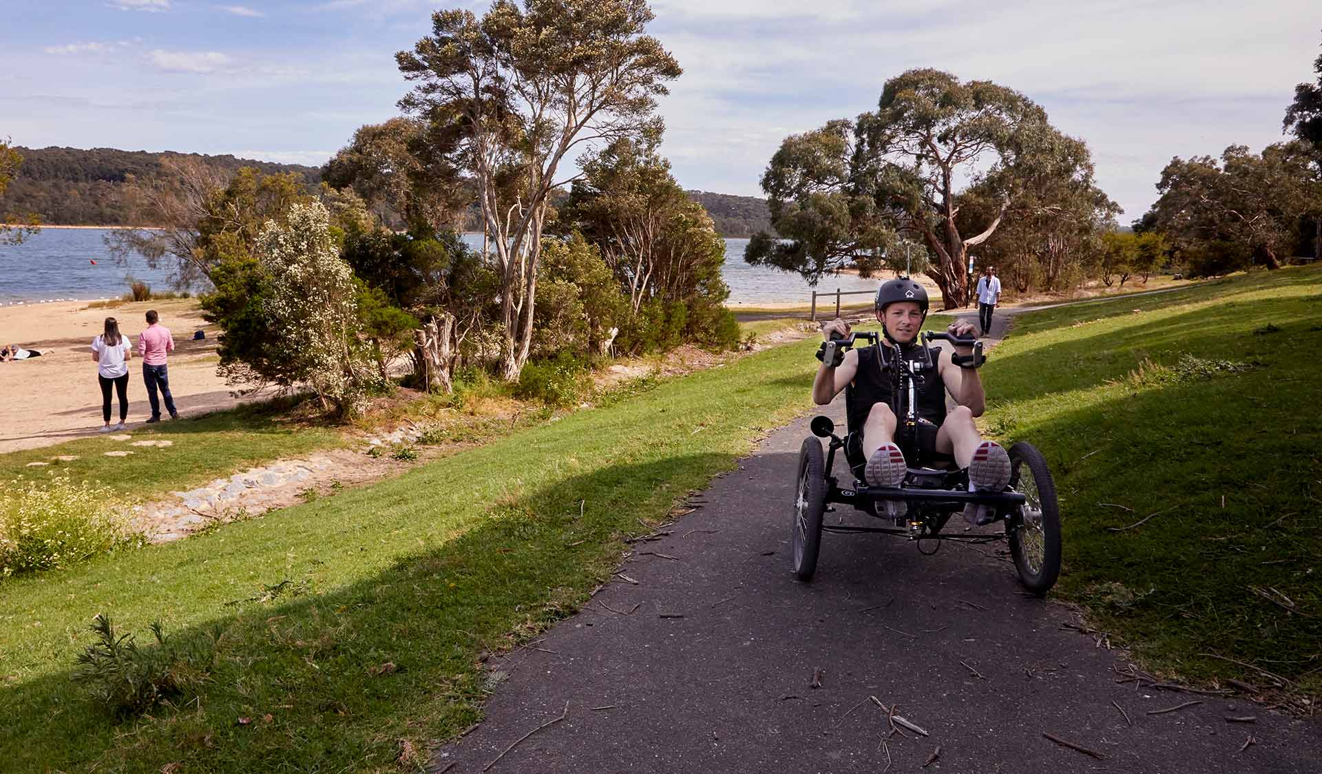A man hand cycles on a sealed path near Lysterfield Lake.