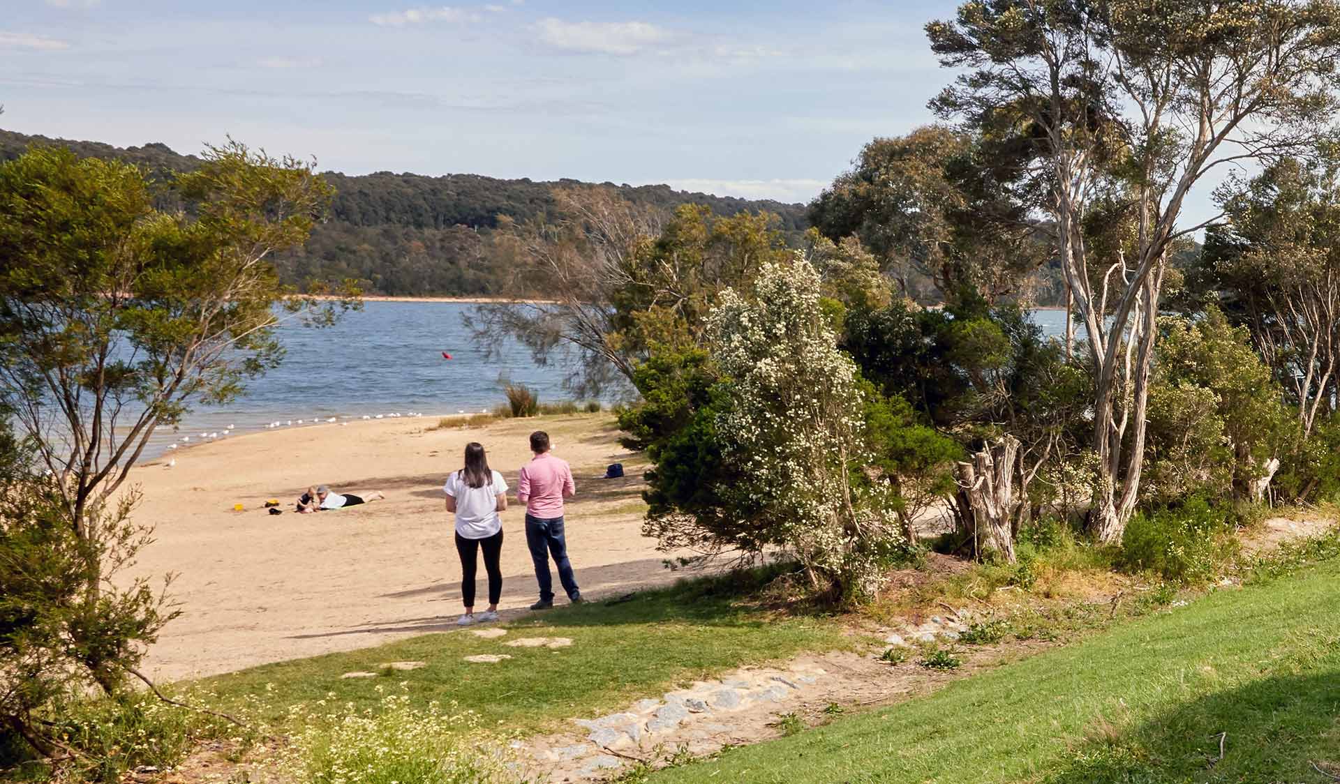 A couple look out over the water from the beach at Lysterfield Lake. 