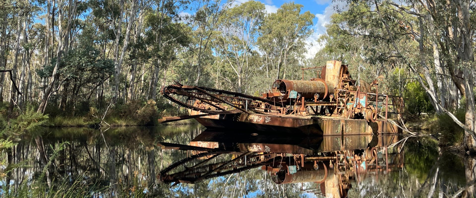 A rusted dredge floats on the river, a remnant of the area's past commercial operations.