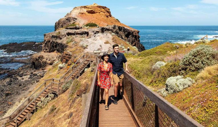 A young couple walk along the board walk at Cape Schank. 