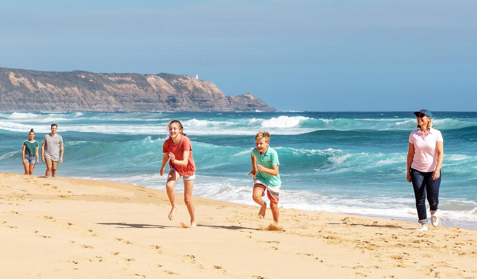 A mother watching her son and daughter race along the sand at Gunnamatta Beach