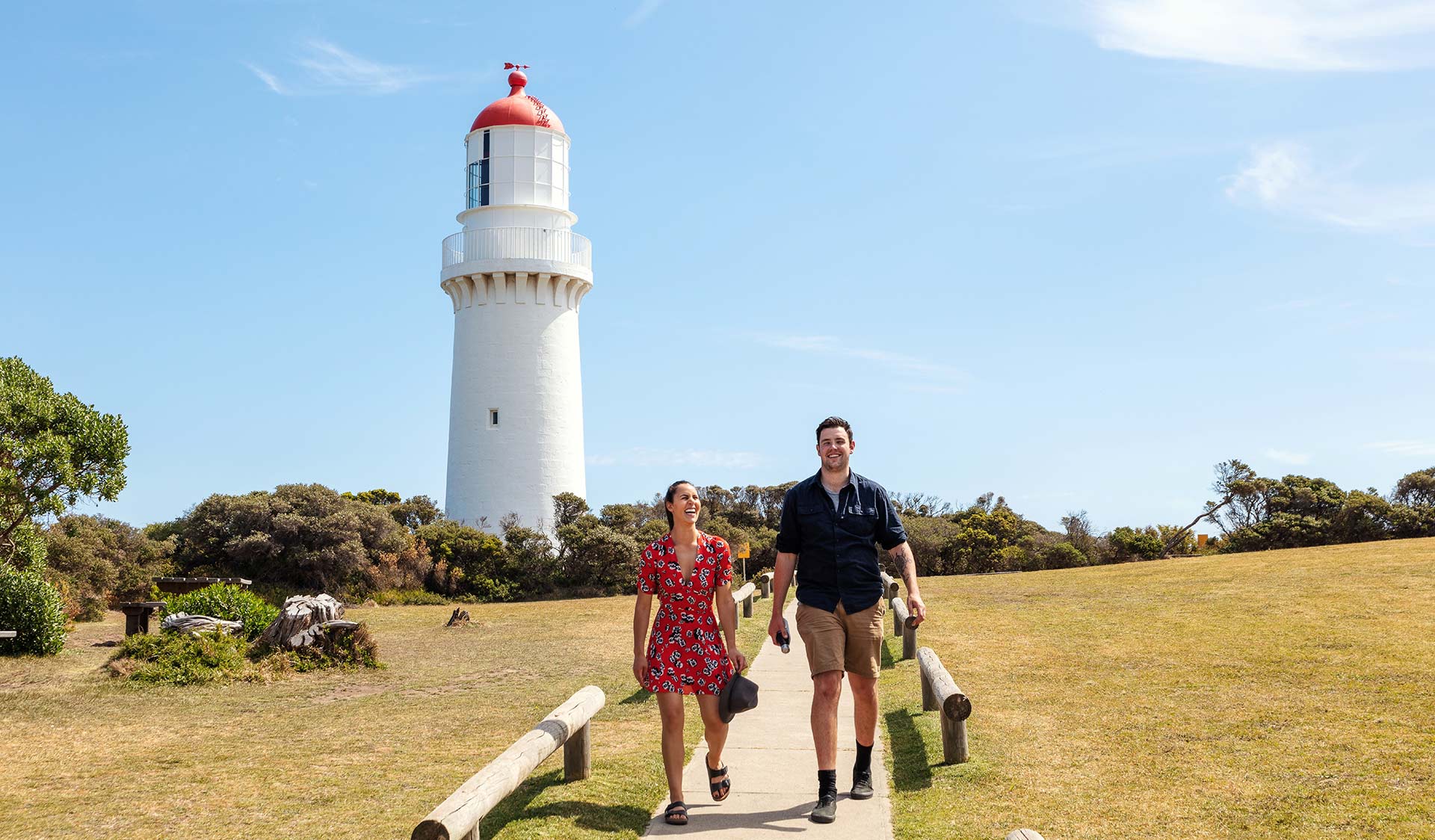 A couple walking along a path away from the Cape Schanck Lighthouse