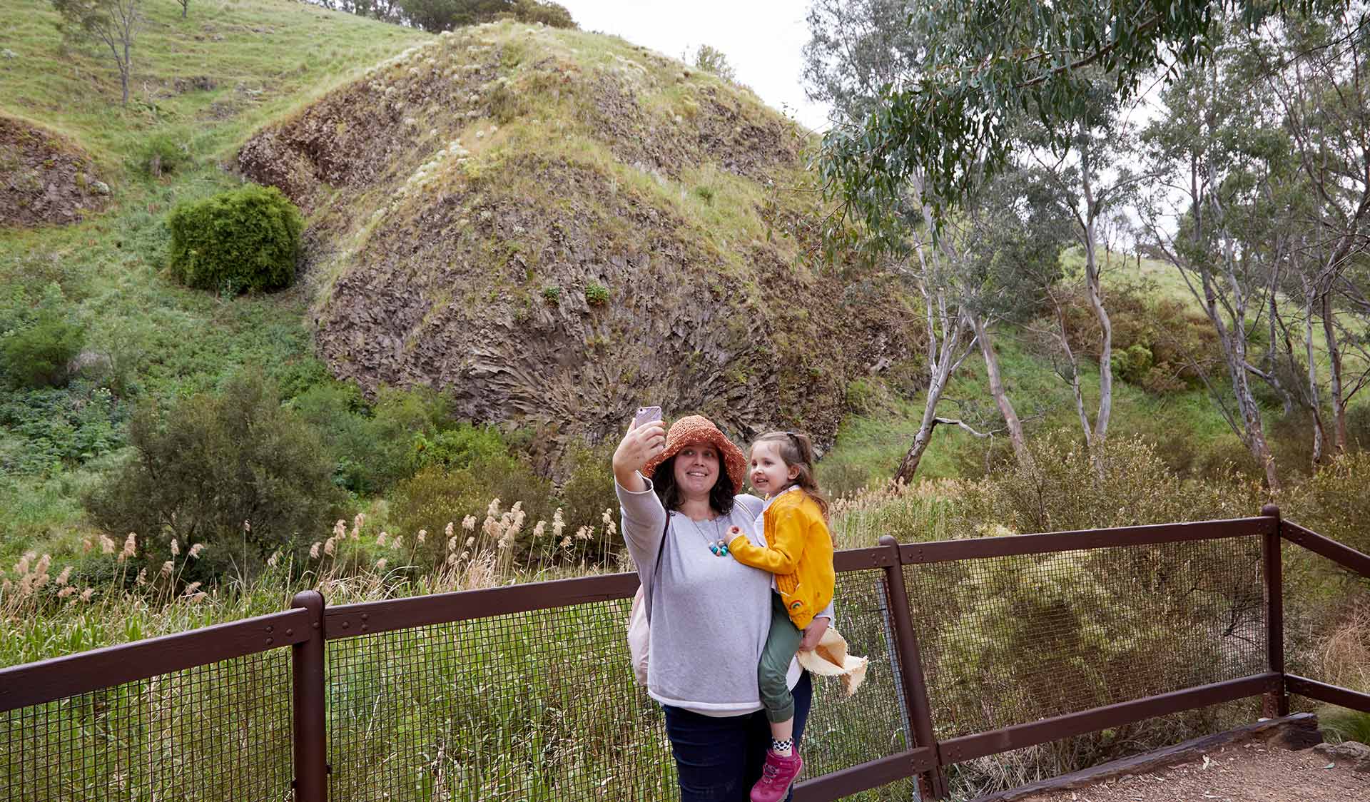 A women and her infant child stop to take a selfie in front of Rosette Rock in Organ Pipes National Park.