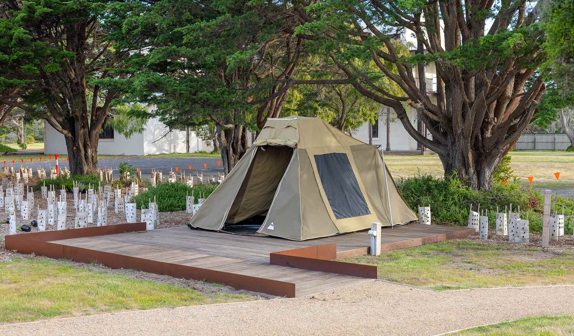 A tent set up on wood flooring in a coastal landscape. A ramp leads to the entrance.