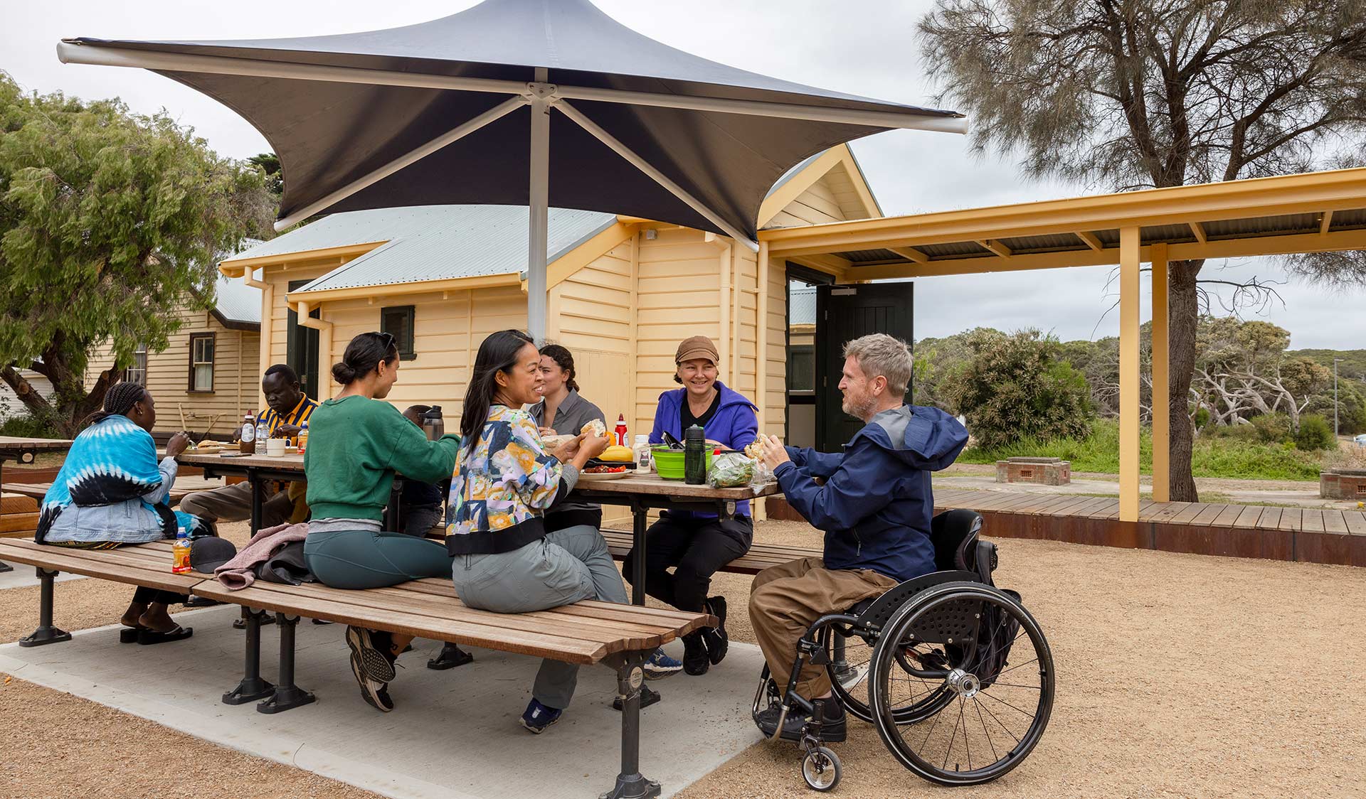 A group of campers enjoy lunch on the shared picnic tables