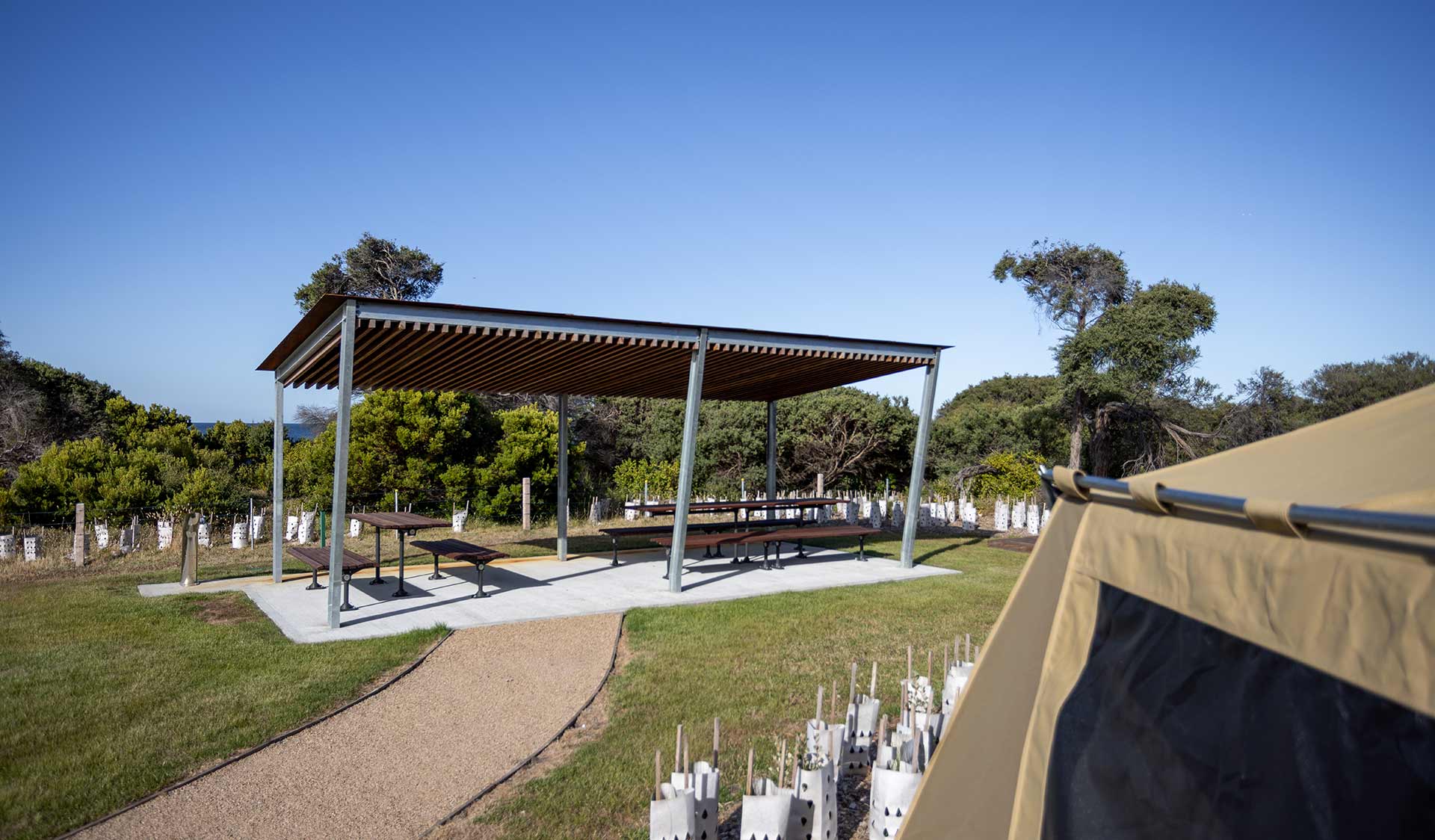Picnic tables under shelter in a coastal landscape. 
