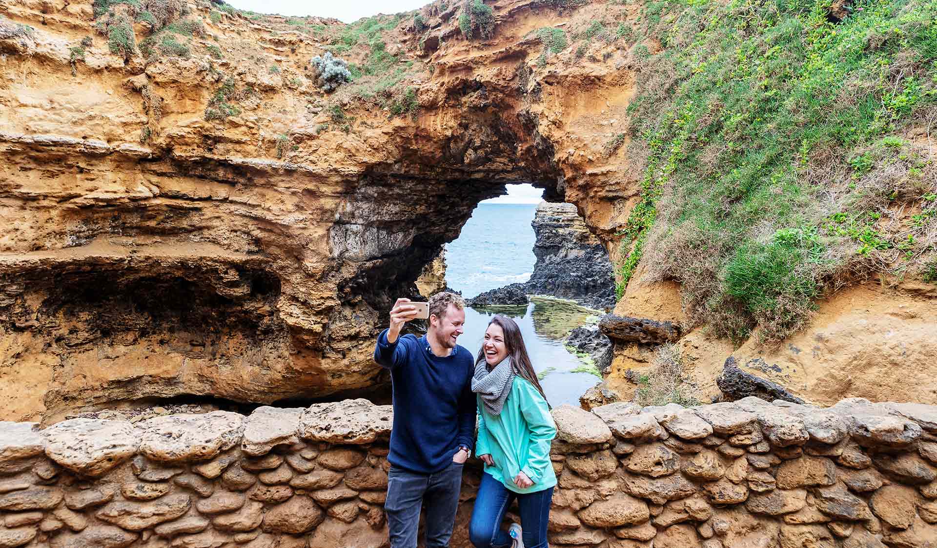 A couple take a selfie in front of the Grotto in Port Campbell National Park.