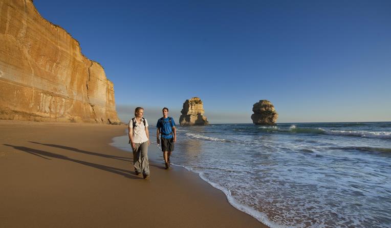 A couple walk along the beach at Gibson Steps.