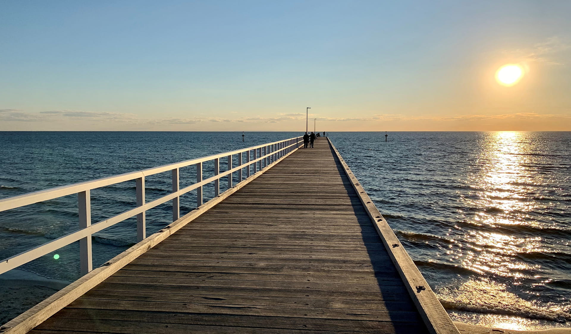 A wooden pier over the water at sunset.
