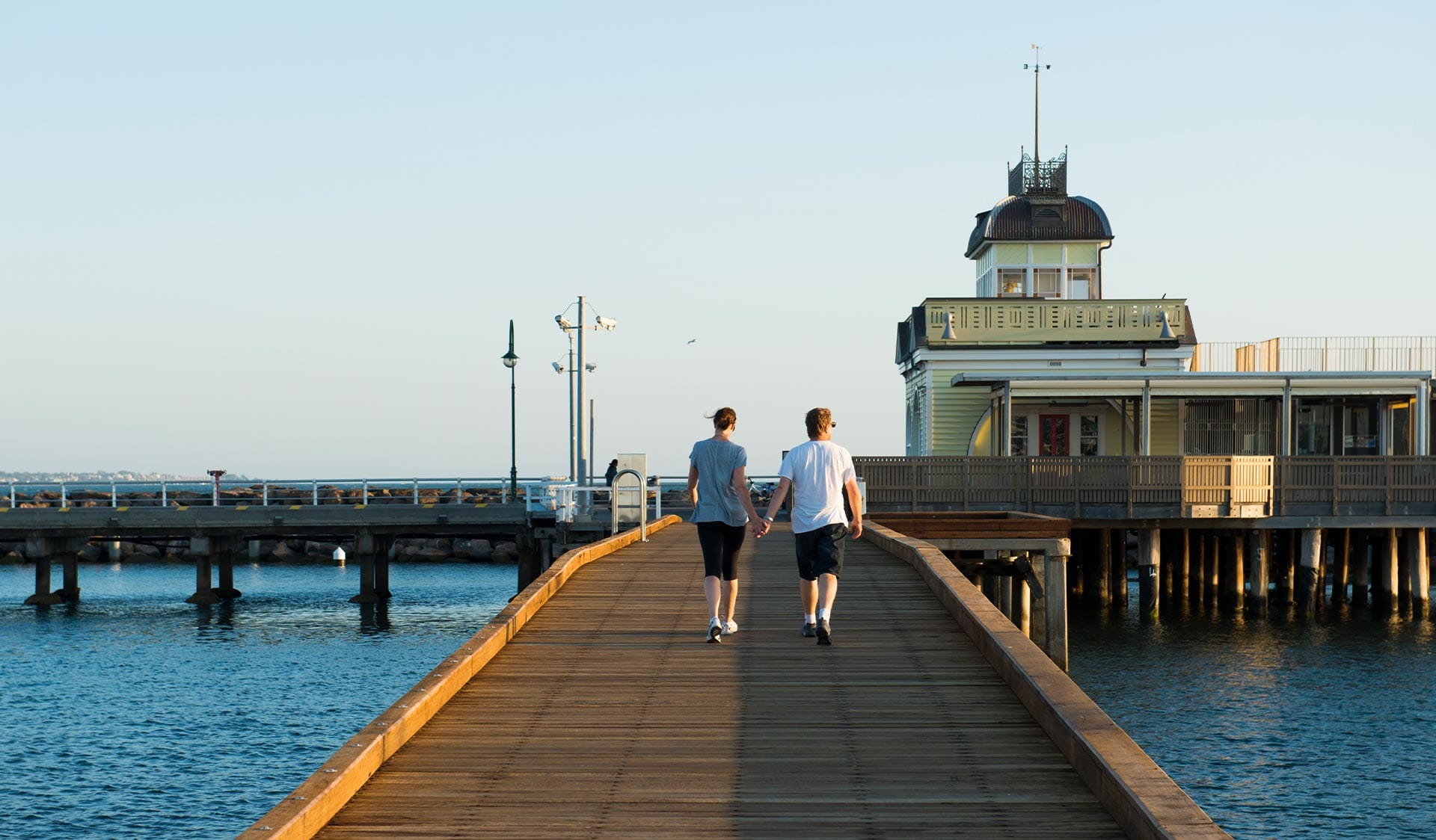 A couple walks along St Kilda Pier