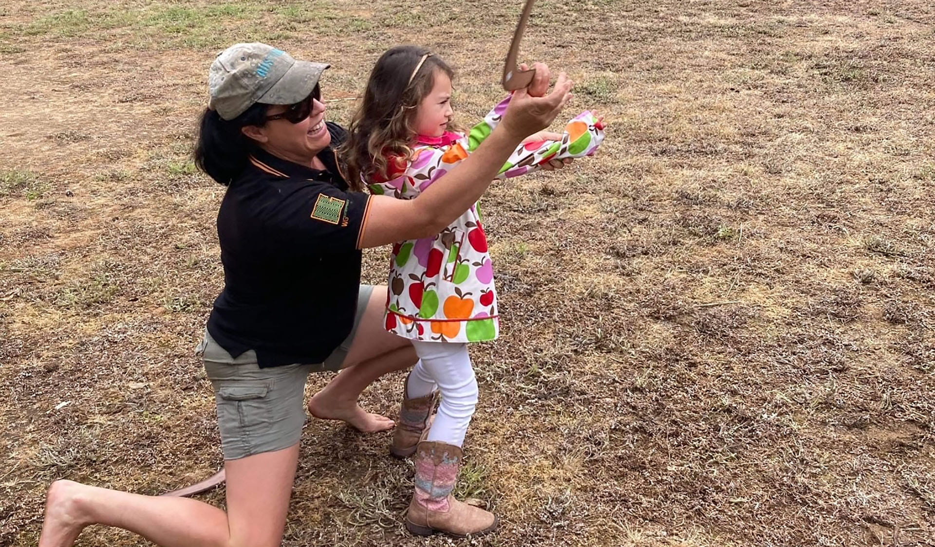 A woman teaching child how to throw a boomerang.