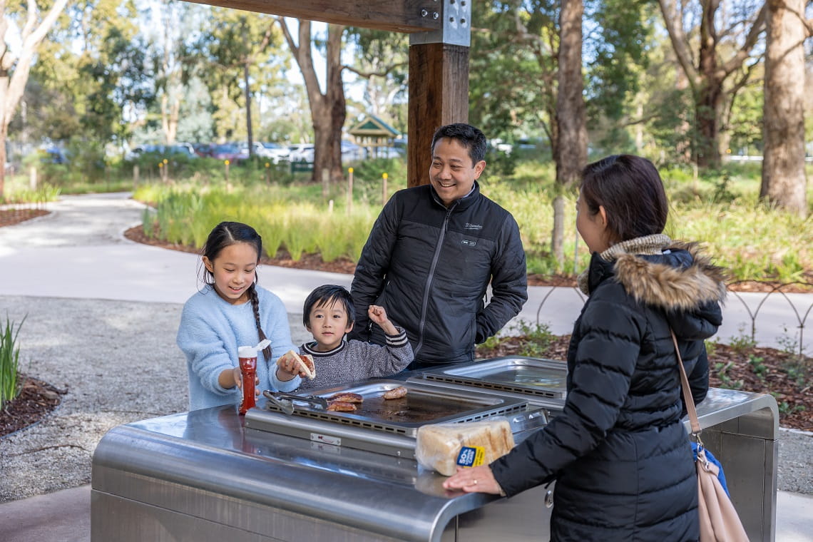 A family have a barbecue at the Wattle Park picnic area.
