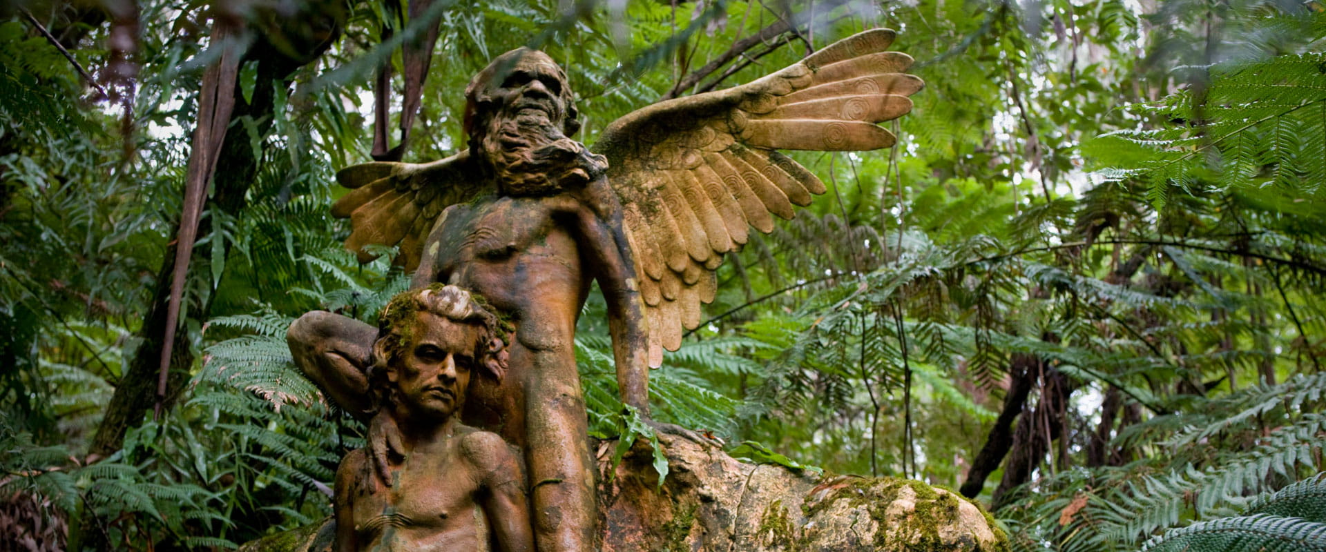 Sculpture by William Ricketts surrounded by lush green foliage. 