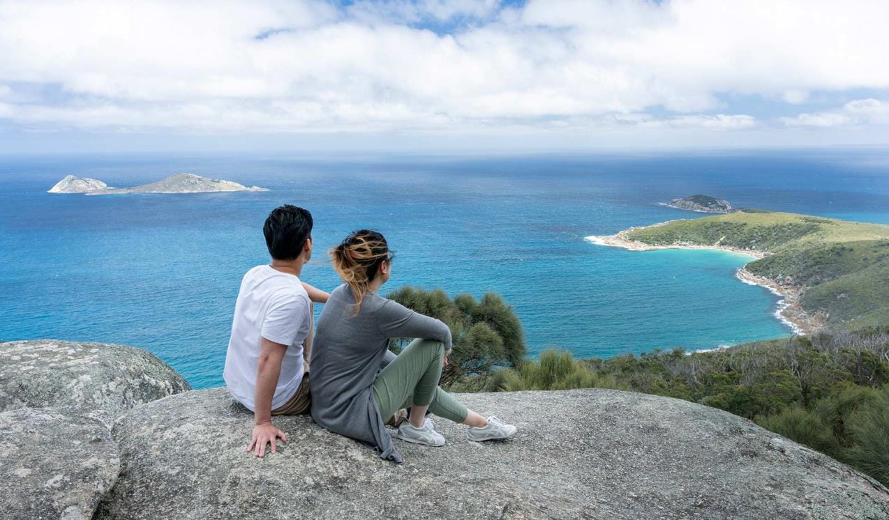 A couple stop to enjoy the view of the ocean sat upon a granite boulder at Tongue Point.