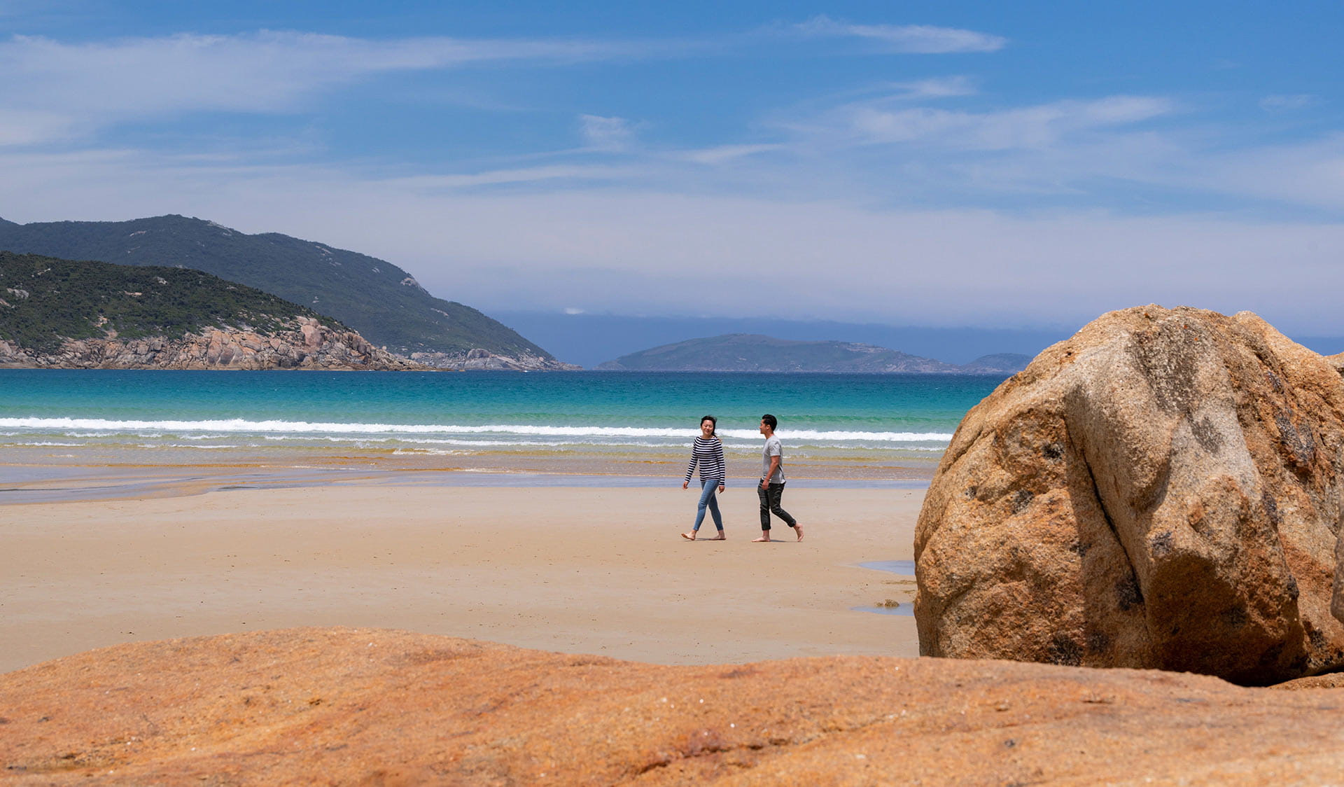 Two people walk along a pristine beach on Wilsons Promontory.