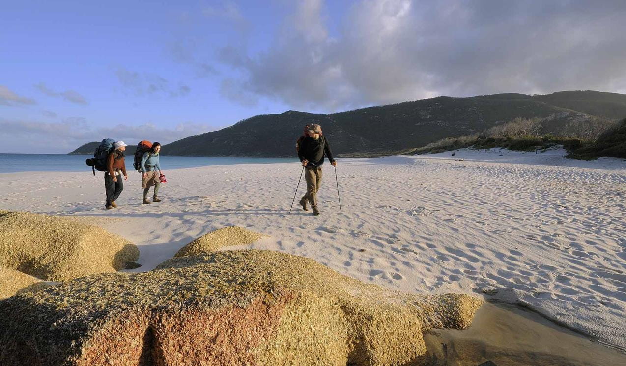 Three hikers walk along the beach at Wilson Promontory National Park.  