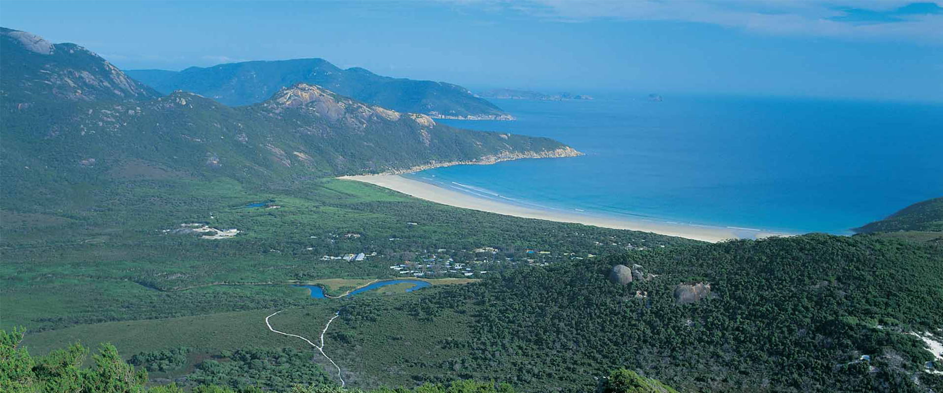 A spectacular coastal view with a large beach and a distant island