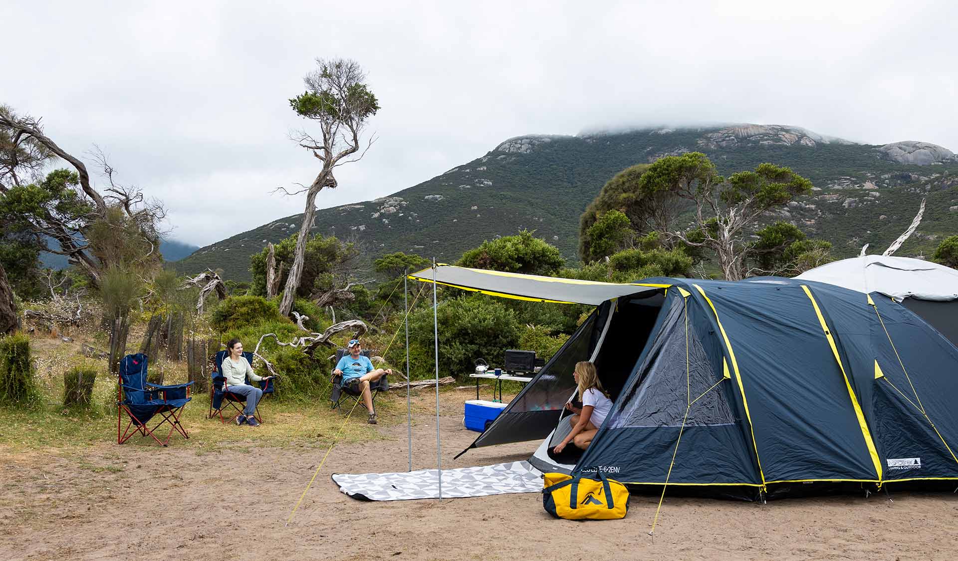A women pokes her head out of her tent in front of Mount Oberon at Tidal River Campground at Wilsons Promontory National Park