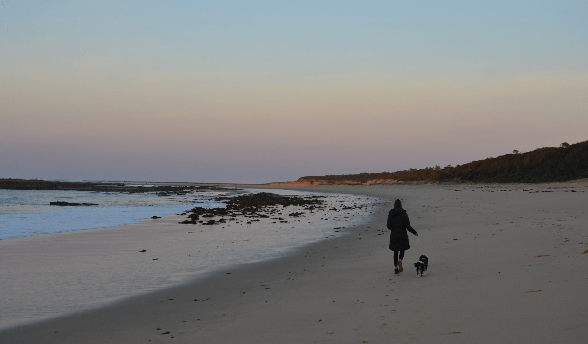 A woman walking her dog along the beach at Undertow Bay in Yallock-Bulluk Marine and Coastal Park