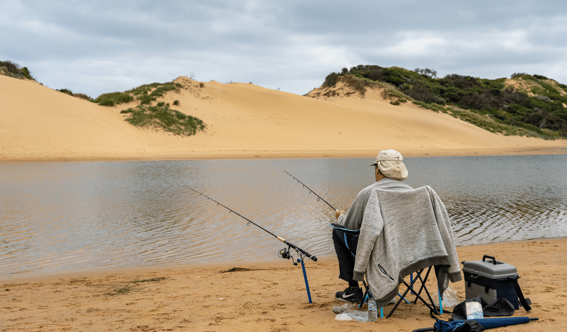 A man sits on a chair while fishing at Powlett River