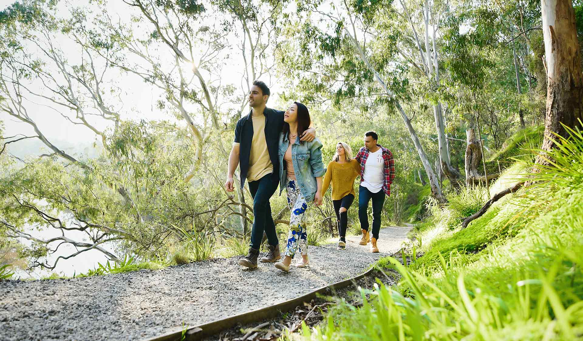 Four friends walk alongside the Yarra River through Yarra Bend Park.