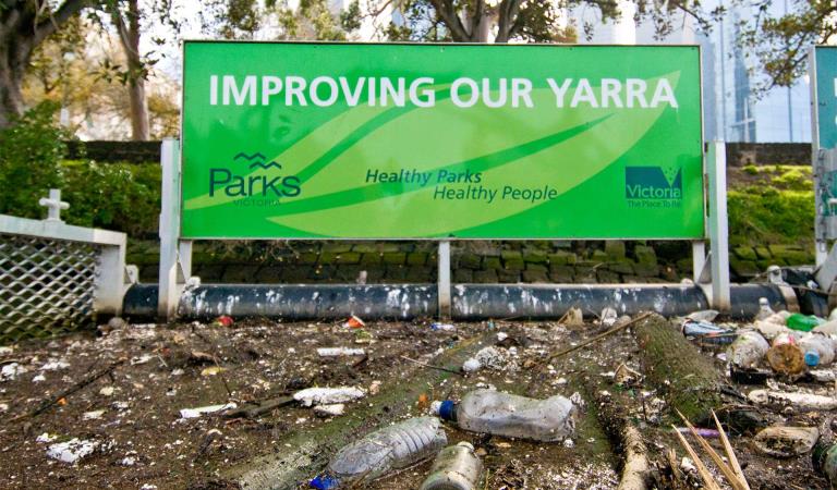 A close up of a litter trap, with rubbish and debris in the foreground, and an Improving Our Yarra sign in the background.