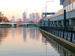 A cyclist follows the bike path along the Yarra River heading in to the Melbourne CBD at sun set.